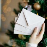 Hand holding stack of craft paper envelopes for christmas greeting card